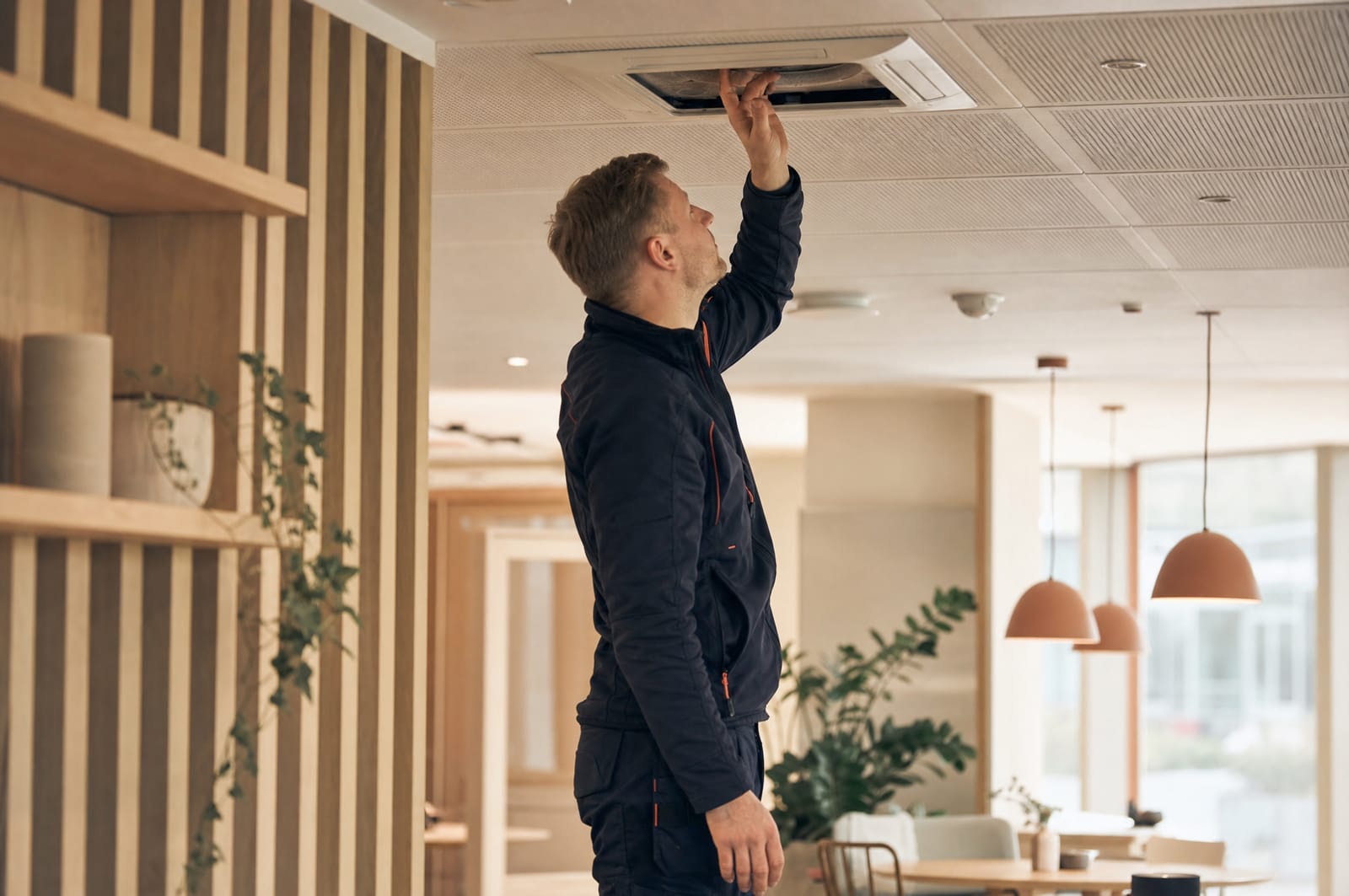 Servicetekniker udfører planlagt eftersyn af ventilationsanlæg i et moderne kontormiljø